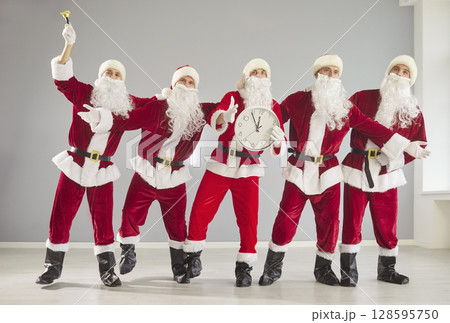 Happy New Year cute group dancing with clocks, partying wearing Santa Claus holiday costume 128595750