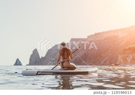 Woman Paddleboarding Ocean Coastline Relaxing Woman Paddleboarding Ocean Coastline Relaxing 128596013
