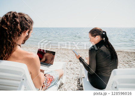 Man woman laptop sea. Working remotely on seashore. Happy successful couple, freelancers working on sea beach, relieves stress from work to restore life balance. Freelance, remote work on vacation Man woman laptop sea. Working remotely on seashore. Happy successful couple, freelancers working on sea beach, relieves stress from work to restore life balance. Freelance, remote work on vacation 128596016