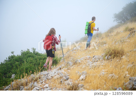 Two Hikers on a Rocky Hillside in Foggy Weather Embracing Nature 128596089