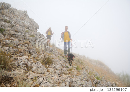Foggy Mountain Hike with Couple and Dog Enjoying Nature Foggy Mountain Hike with Couple and Dog Enjoying Nature 128596107
