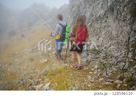 Couple Hiking Through Foggy Mountain Trail Surrounded by Nature Couple Hiking Through Foggy Mountain Trail Surrounded by Nature 128596110