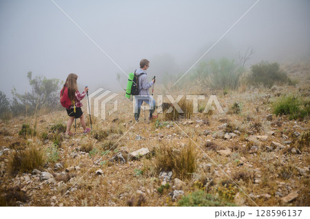 Two Hikers Exploring a Misty Mountain Landscape in Nature 128596137