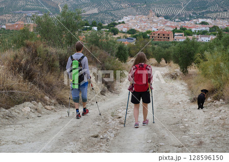 Couple of Hikers Enjoying a Scenic Mountain Trail with Dog Companion 128596150