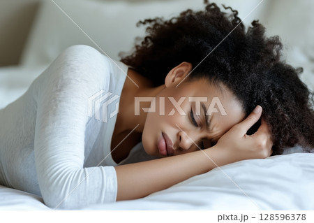 Woman Experiencing Emotional Distress While Lying on Bed in a Cozy Indoor Setting 128596378