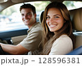Happy Young Couple Enjoying a Road Trip While Sitting Inside Their Car on a Sunny Day 128596381