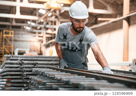 Taking care of metal products. Young factory worker in grey uniform 128596909
