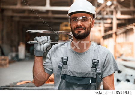Holding the cutters. Young factory worker in grey uniform Holding the cutters. Young factory worker in grey uniform 128596930