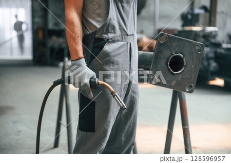 Holding welding equipment. Close up view of man that is working at the factory Holding welding equipment. Close up view of man that is working at the factory 128596957