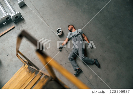 Accident, male factory worker fell, without consciousness, lying down on the floor Accident, male factory worker fell, without consciousness, lying down on the floor 128596987