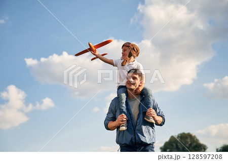 With aviator glasses, playing with toy plane. Father and little son are having fun outdoors With aviator glasses, playing with toy plane. Father and little son are having fun outdoors 128597208