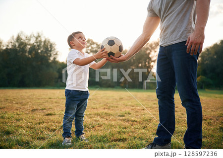 Boy is taking soccer ball. Father and little son are playing and having fun outdoors 128597236