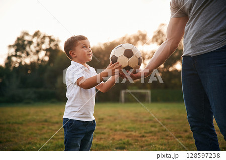 Boy is taking soccer ball. Father and little son are playing and having fun outdoors 128597238