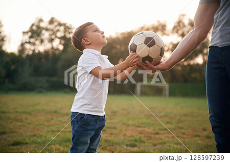 Boy is taking soccer ball. Father and little son are playing and having fun outdoors 128597239