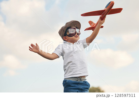 Retro style aviator glasses, with toy plane. Little boy is playing outdoors at daytime Retro style aviator glasses, with toy plane. Little boy is playing outdoors at daytime 128597311