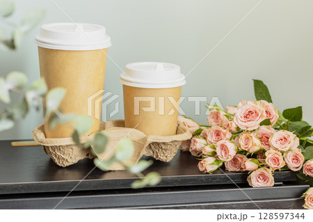 Spring romantic holiday composition with two disposable cups of coffee and bouquet of roses on wooden table. Dating or love concept. coffee to go. Mothers day, womans day, birthday or valentines day Spring romantic holiday composition with two disposable cups of coffee and bouquet of roses on wooden table. Dating or love concept. coffee to go. Mothers day, womans day, birthday or valentines day 128597344
