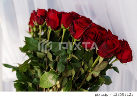 Luxurious Red Roses Bouquet - Close-up of Vibrant Velvet Flowers. Romantic Gift Idea with Deep Crimson Blooms Against a Soft White Background 128598123