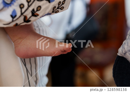 Newborn Baby Foot Held by Parents, Gentle Touch, Intimate Family Moment, Soft White and Blue Clothing, Close-up, Loving Connection. Newborn Baby Foot Held by Parents, Gentle Touch, Intimate Family Moment, Soft White and Blue Clothing, Close-up, Loving Connection. 128598138