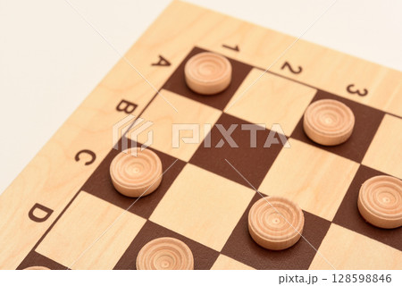 Wooden checkers on the board. The board game checkers. Wooden checkers on the board. The board game checkers. 128598846