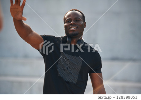 Greeting hand. Handsome black man is posing outdoors at daytime Greeting hand. Handsome black man is posing outdoors at daytime 128599053