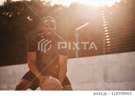 Sunlight outdoors. Young black man is with basketball ball 128599063
