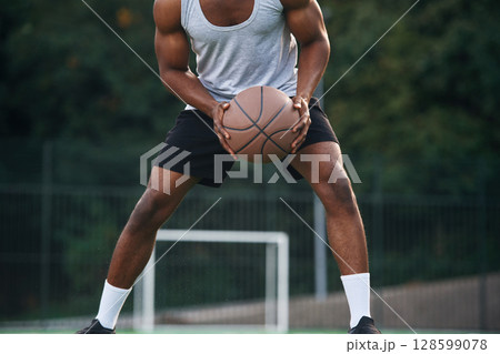 Front view. Young black man is with basketball ball outdoors 128599078