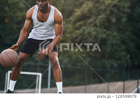 Front view. Young black man is with basketball ball outdoors 128599079