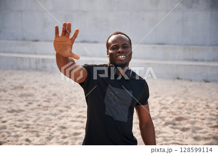 Greeting hand. Handsome black man is posing outdoors at daytime Greeting hand. Handsome black man is posing outdoors at daytime 128599114