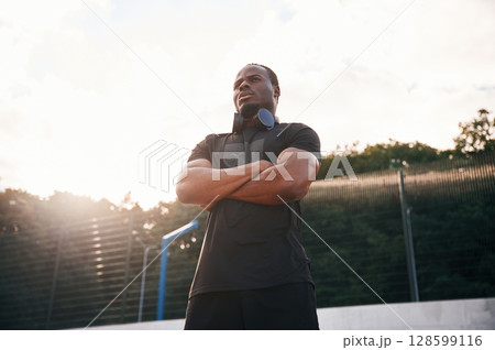Beautiful sunlight. Handsome black man is posing outdoors at daytime Beautiful sunlight. Handsome black man is posing outdoors at daytime 128599116