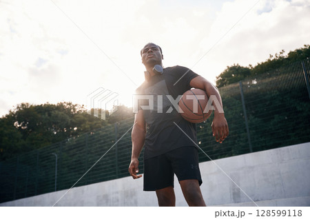 Confident person. Young black man is with basketball ball outdoors 128599118