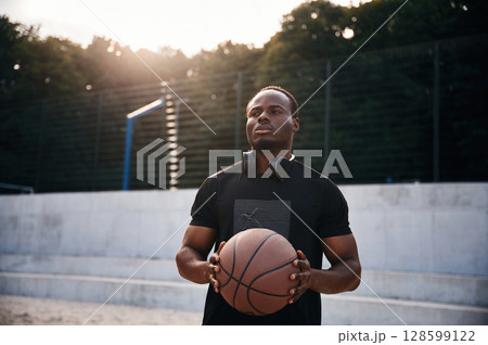 Confident person. Young black man is with basketball ball outdoors Confident person. Young black man is with basketball ball outdoors 128599122