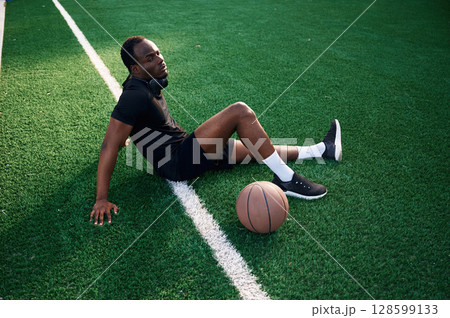 Sitting and relaxing. Young black man is with basketball ball outdoors Sitting and relaxing. Young black man is with basketball ball outdoors 128599133