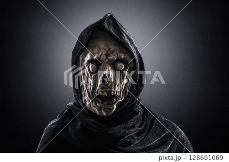 Portrait of a zombie with hooded cape over dark misty background 128601069