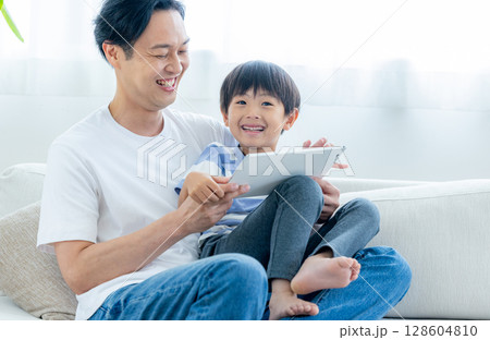 リビングでタブレットを見る家族 リビングでタブレットを見る家族 128604810