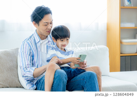 スマホを見るパパと子供 スマホを見るパパと子供 128604849