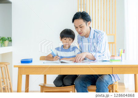 リビングで勉強をする子供と父親 128604868