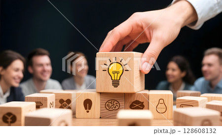 A hand picking up a wooden block with a light bulb icon symbolizing idea and innovation in business meeting environment 128608132