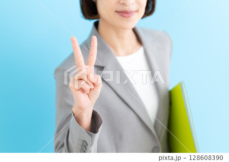 グレーのスーツを着てピースをするミドル女性ビジネスウーマン グレーのスーツを着てピースをするミドル女性ビジネスウーマン 128608390