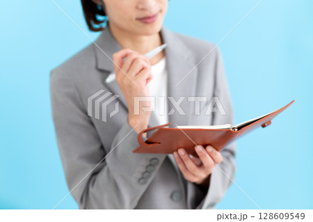 スーツを着て手帳を持って悩むミドル女性ビジネスウーマン スーツを着て手帳を持って悩むミドル女性ビジネスウーマン 128609549