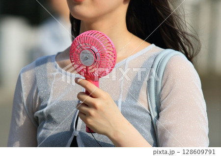 ハンディファンを持って歩く女性 128609791