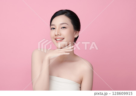 A beautiful young Asian woman with clean, fresh skin against a pink background. Skincare, facial treatment, cosmetology, beauty, and spa. An elegant portrait of an Asian woman. 128609915