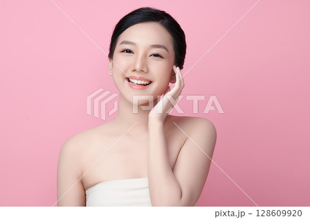A beautiful young Asian woman with clean, fresh skin against a pink background. Skincare, facial treatment, cosmetology, beauty, and spa. An elegant portrait of an Asian woman. A beautiful young Asian woman with clean, fresh skin against a pink background. Skincare, facial treatment, cosmetology, beauty, and spa. An elegant portrait of an Asian woman. 128609920