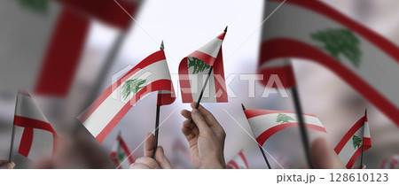Lebanon flags in their hands on a blurred urban background 128610123