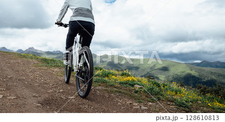 People riding mountain bike on flowering grassland mountain trail 128610813