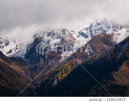 Aerial view of beautiful autumn forest landscape and snow capped mountains Aerial view of beautiful autumn forest landscape and snow capped mountains 128610825