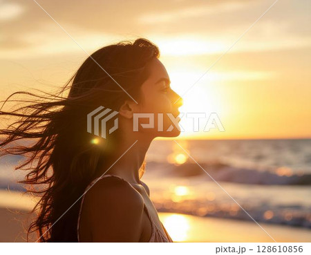 海辺で夕陽に微笑む女性の横顔 128610856