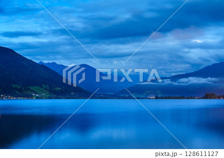 Tranquil Blue Hour Scene Serene Lake Reflecting Majestic Mountains and Cloudy Sky Vista 128611127