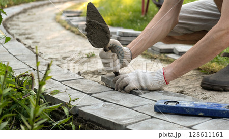 Laying paving stones on cement mortar. Laying a garden path made of tiles. Self-laying of concrete paving slabs in the courtyard of the house. do it yourself. DIY 128611161