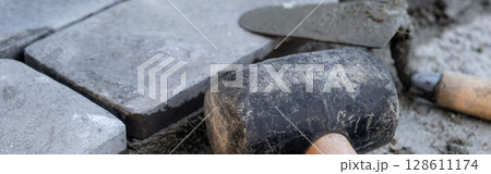 Laying paving stones on cement mortar. Banner. Laying a garden path made of tiles. Self-laying of concrete paving slabs in the courtyard of the house. do it yourself. DIY 128611174