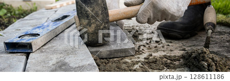 Laying paving stones on cement mortar. Banner, Laying a garden path made of tiles. Self-laying of concrete paving slabs in the courtyard of the house. do it yourself. DIY Laying paving stones on cement mortar. Banner, Laying a garden path made of tiles. Self-laying of concrete paving slabs in the courtyard of the house. do it yourself. DIY 128611186